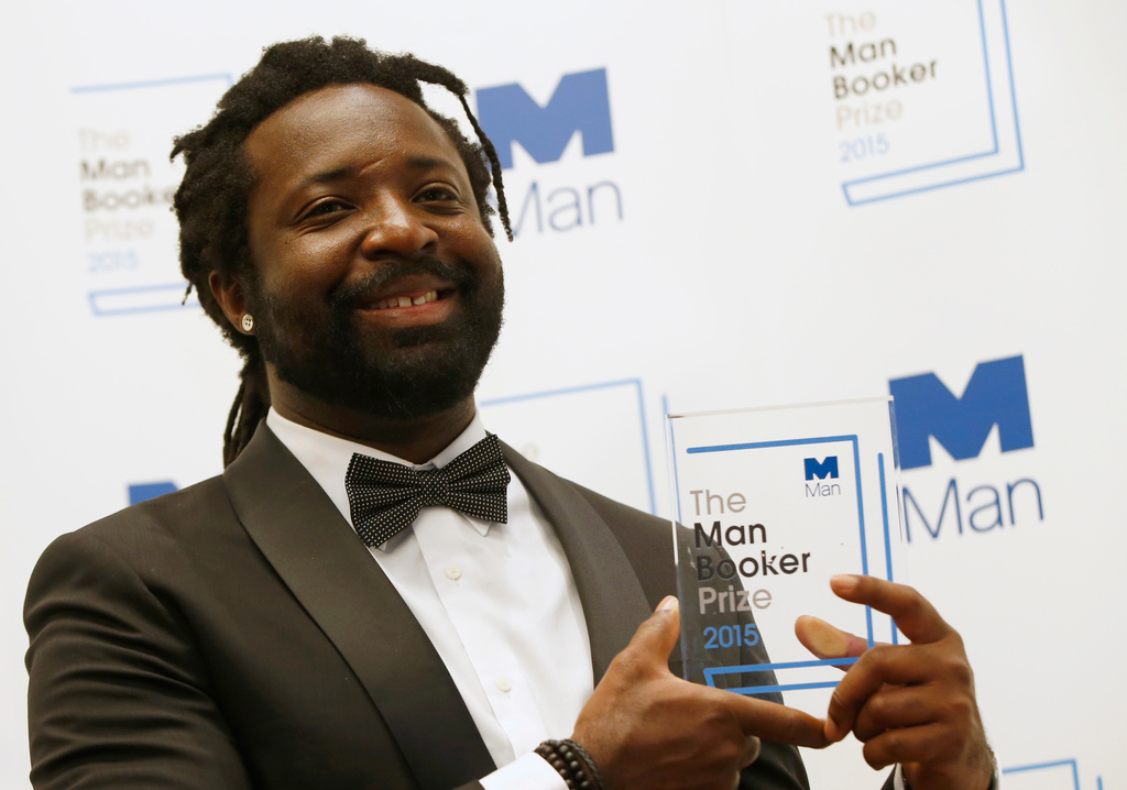 FILE - Jamaican author Marlon James poses with the award after his book, "A Brief History of Seven Killings," was named as winner of the 2015 Booker Prize for Fiction in London on Oct. 13, 2015. (AP Photo/Alastair Grant, File)