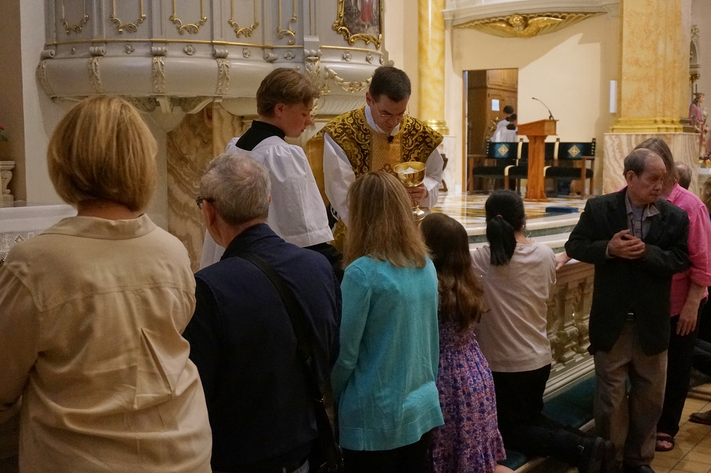 The faithful at the Church of Saint Agnes receive communion on the tongue and while kneeling at the altar rails, in the traditional custom, during one of the Catholic parish’s Latin Masses in St. Paul, Minn., Sunday, June 28, 2026. (AP Photo/Giovanna Dell’Orto)