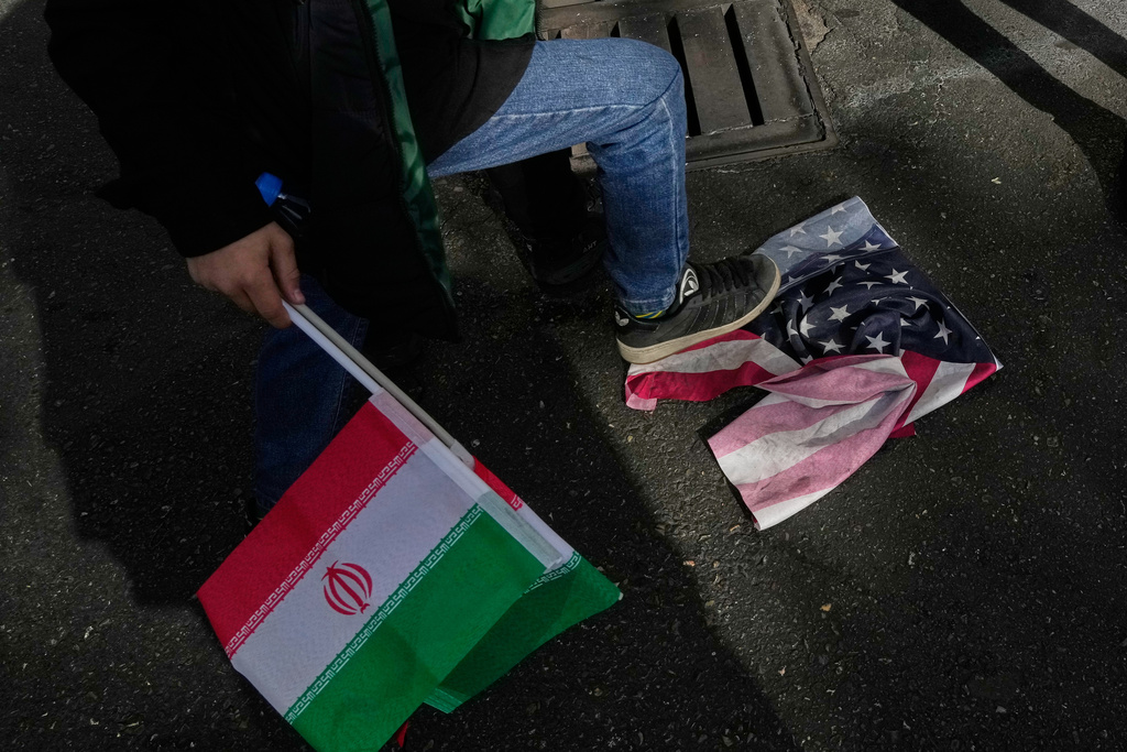 A school boy stomps a U.S. flag as he holds an Iranian flag during an annual rally in front of the former U.S. Embassy in Tehran, celebrating the anniversary of the 1979 takeover of the embassy, Iran, Tuesday, Nov. 4, 2025. (AP Photo/Vahid Salemi)