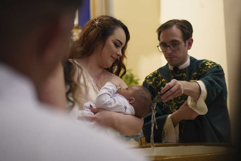 Gabriela Plasencia, originally from the Mexican state of Jalisco, holds her 4-month-old nephew Gael as he's baptized at Immaculate Conception Catholic Church on Sunday, Aug. 10, 2025, in Cedar Rapids, Iowa. (AP Photo/Jessie Wardarski)