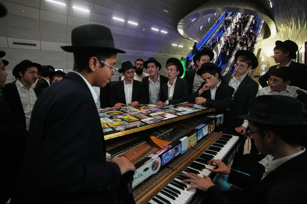 Ultra-Orthodox Jewish men play music before boarding a train following a rally protesting plans to require them to serve in the Israeli military, in Jerusalem, Thursday, Oct. 30, 2025. (AP Photo/Ohad Zwigenberg)