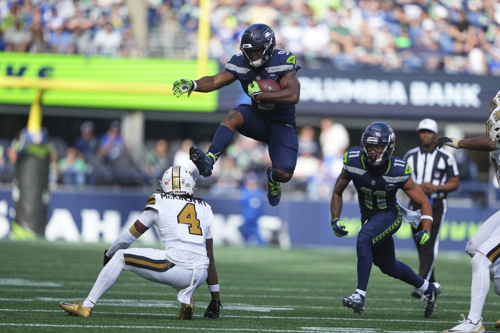 Seattle Seahawks running back Kenneth Walker III (9) leaps over New Orleans Saints cornerback Kool-Aid McKinstry (4) in the second half of an NFL football game, Sunday, Sept. 21, 2025, in Seattle. (AP Photo/Lindsey Wasson)