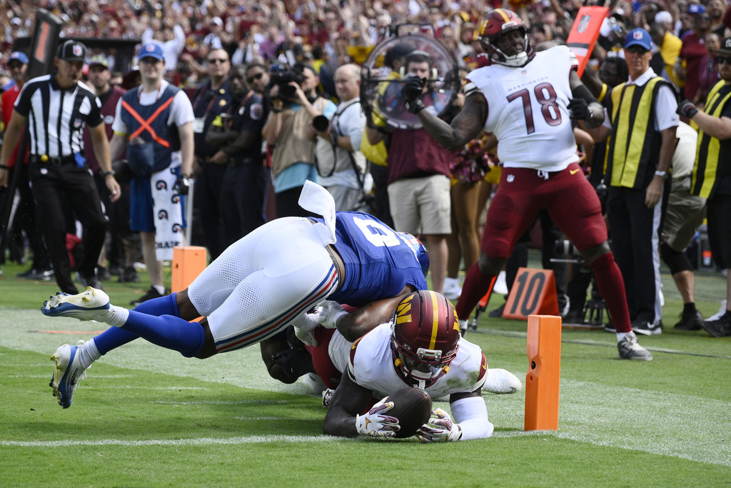 Washington Commanders wide receiver Deebo Samuel (1) diving in to score a touchdown against New York Giants safety Jevon Holland (8) during the second half of an NFL football game, Sunday, Sept. 7, 2025, in Landover, Md. (AP Photo/Nick Wass)