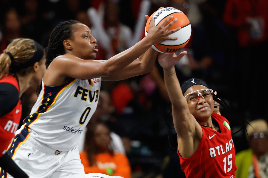 Indiana Fever guard Kelsey Mitchell (0) and Atlanta Dream guard Allisha Gray (15) reach for a loose ball during the first half of Game 3 in the first round of the WNBA basketball playoffs, Thursday, Sept. 18, 2025, in Atlanta. (AP Photo/Butch Dill)