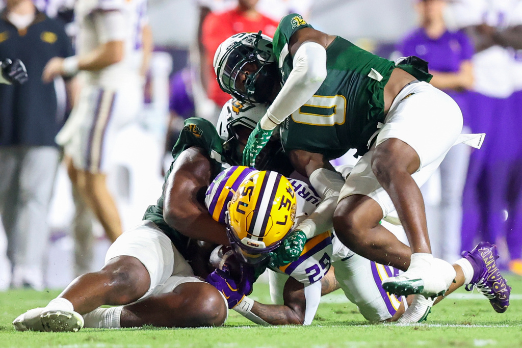 Southeastern Louisiana defensive lineman Kaleb Proctor (2) and KK Reno (0) tackle LSU running back Caden Durham (29) in the first half of an NCAA college football game in Baton Rouge, La., Saturday, Sept. 20, 2025. (AP Photo/Peter Forest)
