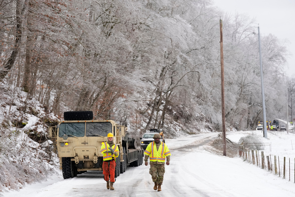 Tennessee National Guard members Taylor Osteen, left, and Antuwan Powell walk along an ice covered road as they work to remove trees Friday, Jan. 30, 2026, in Nashville, Tenn. (AP Photo/George Walker IV)