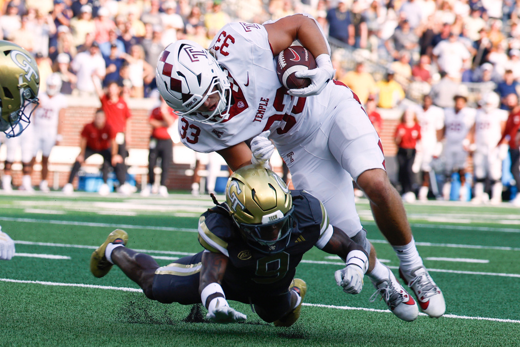 Temple tight end Ryder Kusch (33) is tripped by Georgia Tech defensive back Omar Daniels, bottom, as he carries the ball during the first half of an NCAA college football game, Saturday, Sept. 20, 2025, in Atlanta. (AP Photo/Butch Dill)