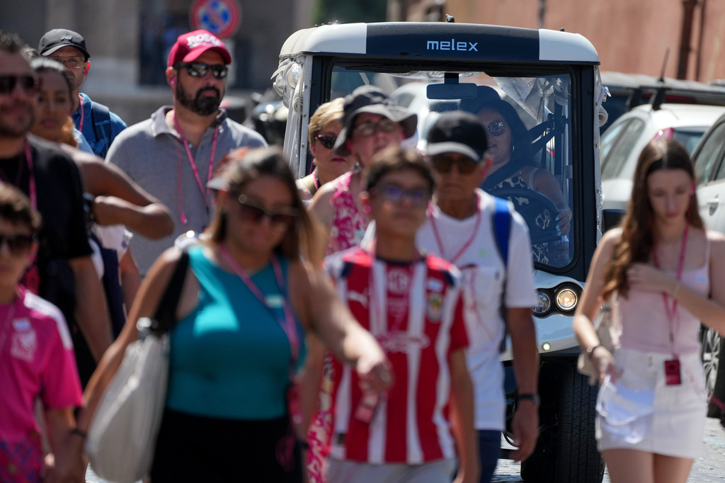 A golf cart makes its way through crowds of tourists in Rome’s historic center, Tuesday, Aug. 18, 2026, amid growing debate over the vehicles’ role in congestion and overtourism. (AP Photo/Gregorio Borgia)