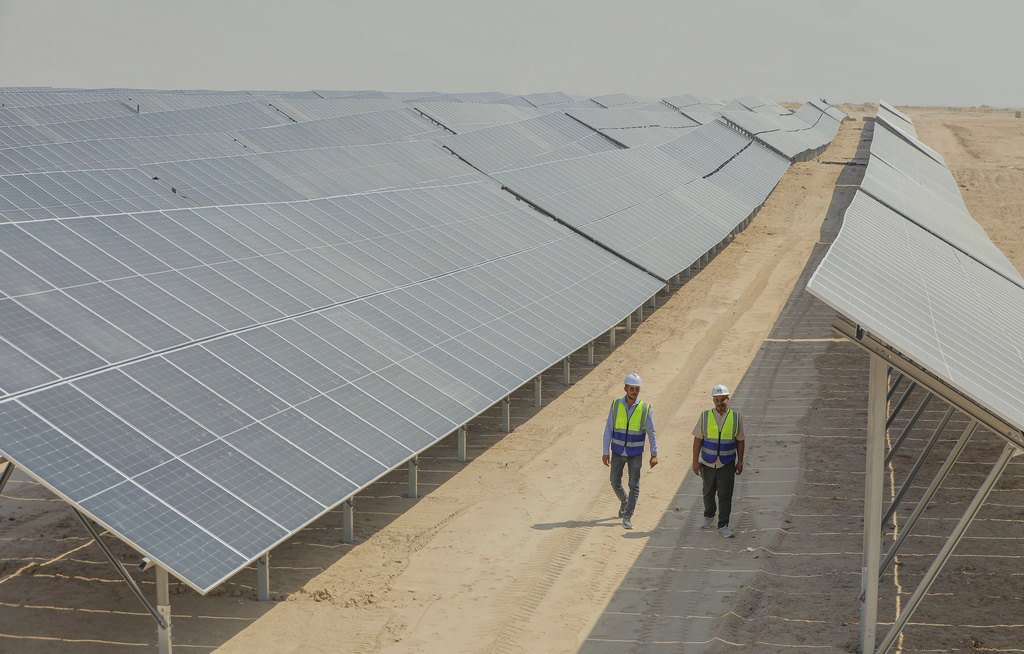 Workers walk between solar panels at a newly opened industrial-scale solar power plant in Karbala, Iraq, Wednesday, Sept. 17, 2025. (AP Photo/Anmar Khalil)
