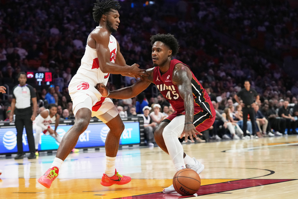 Miami Heat guard Davion Mitchell (45) drives to the basket as Toronto Raptors guard Immanuel Quickley, left, defends during the first half of an NBA basketball game, Tuesday, Dec. 23, 2025, in Miami. (AP Photo/Lynne Sladky)