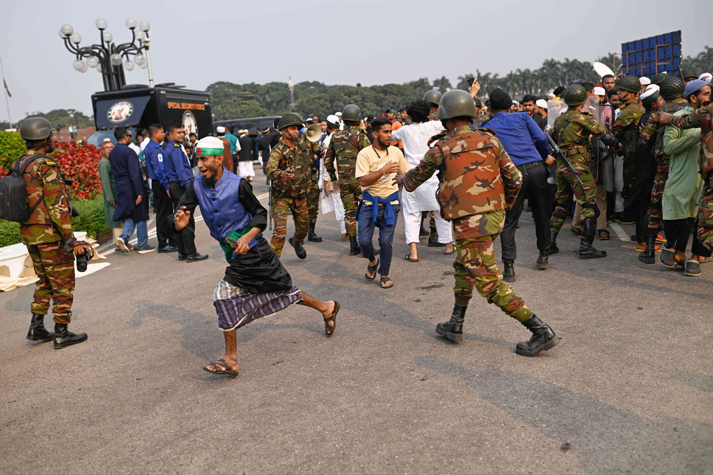 Security forces control a group of people who arrived to participate in the funeral prayers for leading Bangladeshi activist Sharif Osman Hadi, who died from gunshot wounds sustained in an attack in Dhaka earlier this month, in Dhaka, outside the nation's Parliament complex in Dhaka, Bangladesh, Saturday, Dec. 20, 2025. (AP Photo/Mahmud Hossain Opu)