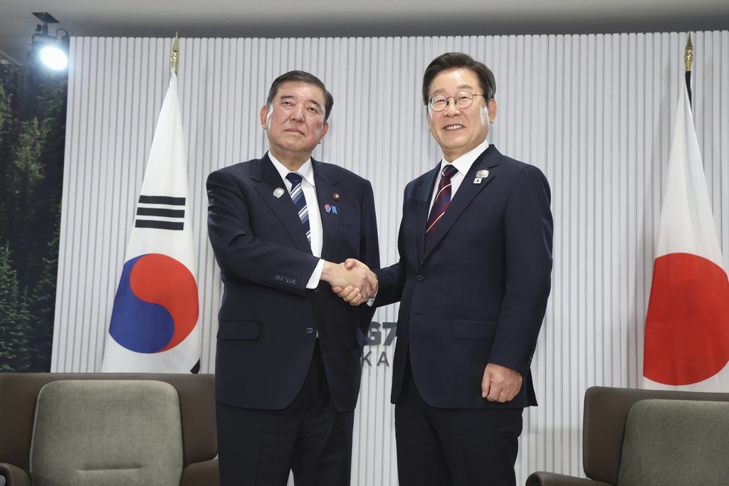 FILE - Japanese Prime Minister Shigeru Ishiba, left, and South Korean President Lee Jae Myung, right, shake hands ahead of a bilateral meeting on the sidelines of the G7, in Kananaskis, Alberta, on June 17, 2025. (Kyodo News via AP, File)