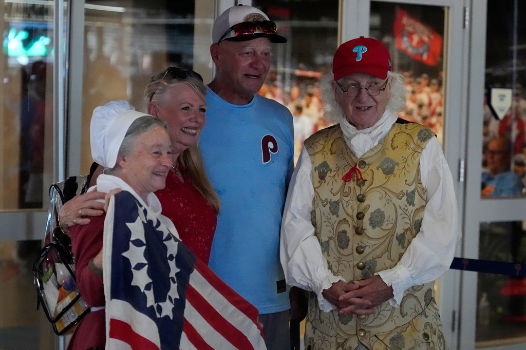 Bill Robling as Benjamin Franklin, right, and Carol Spacht as Betsy Ross, left, pose with Philadelphia Phillies fans before a baseball game between the Phillies and the Pittsburgh Pirates Thursday, July 2, 2026, in Philadelphia. (AP Photo/Matt Slocum)