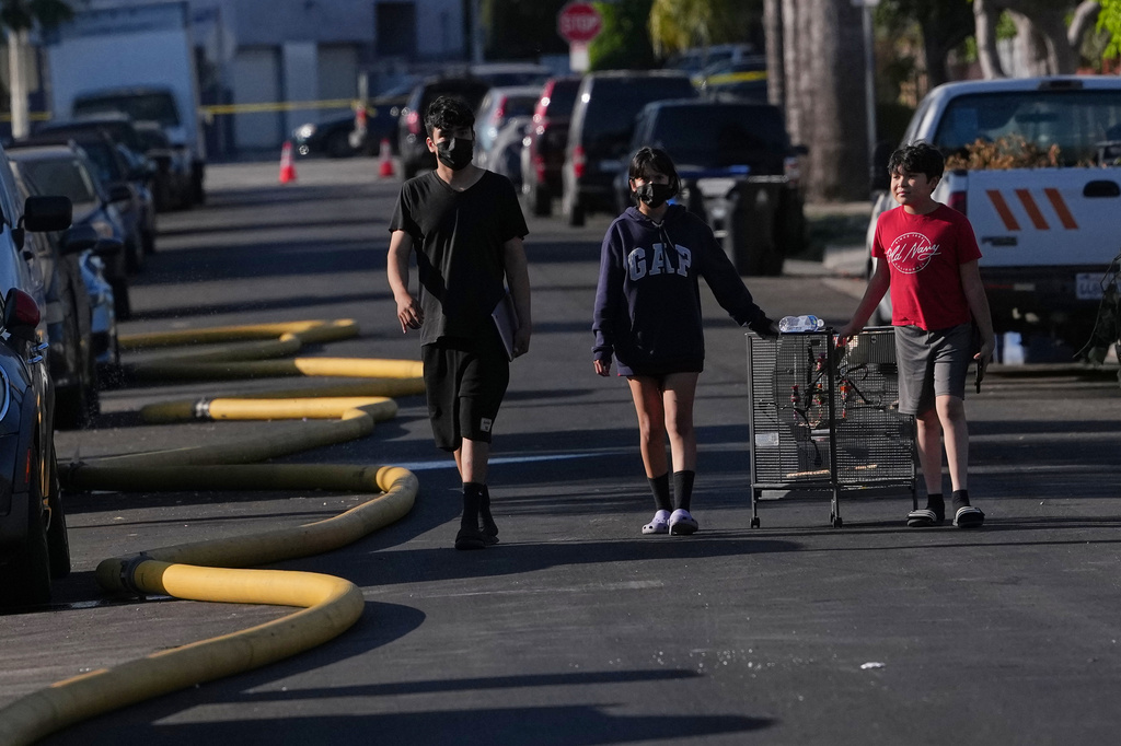 People wear masks near the site of a warehouse fire in the Boyle Heights section of Los Angeles on Wednesday, June 17, 2026. (AP Photo/Jae C. Hong)