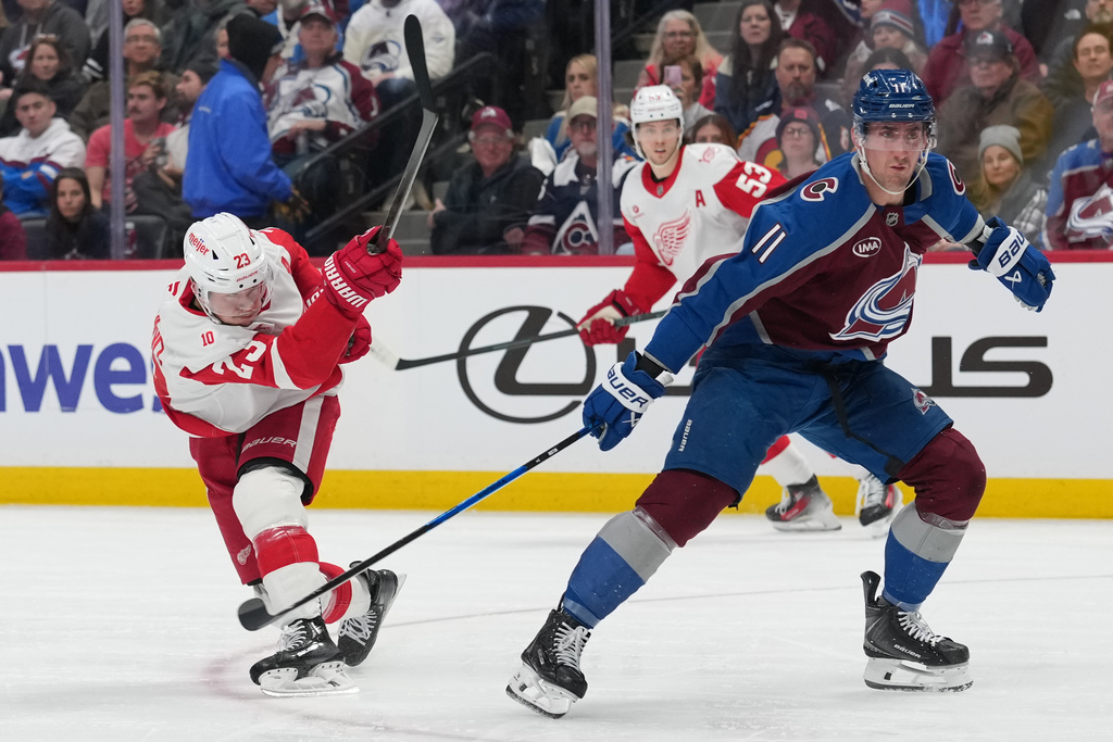 Detroit Red Wings left wing Lucas Raymond, left, shoots the puck past Colorado Avalanche center Brock Nelson, right, in the second period of an NHL hockey game Monday, Feb. 2, 2026, in Denver. (AP Photo/David Zalubowski)