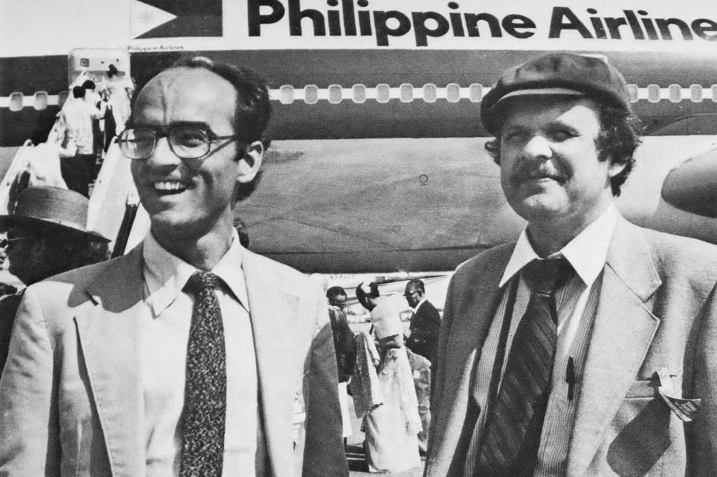 In this undated photo published in The AP World in 1982, Mobile correspondent Garry Mitchell, left, and Manila correspondent David Briscoe, right, attend a visit by Philippine President Ferdinand Marcos at the airport in Mobile, Ala. (AP Photo)