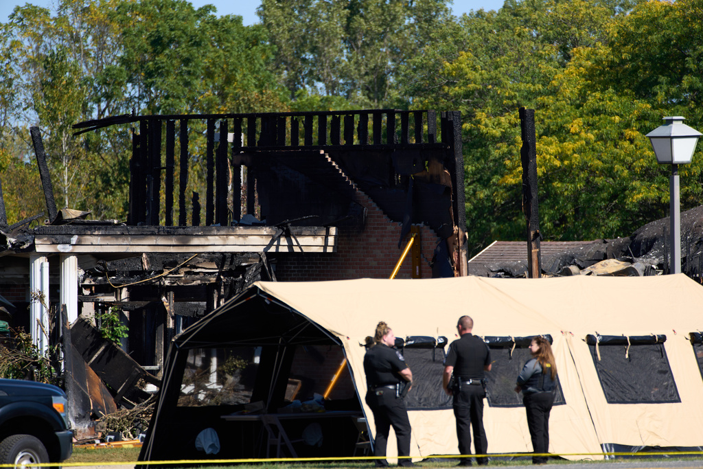 Investigators walk in front of The Church of Jesus Christ of Latter-day Saints in Grand Blanc Township, Mich. where Sunday morning a man rammed his vehicle into the building before opening fire and setting the building ablaze, Tuesday, Sept. 30, 2025. (AP Photo/Ryan Sun)