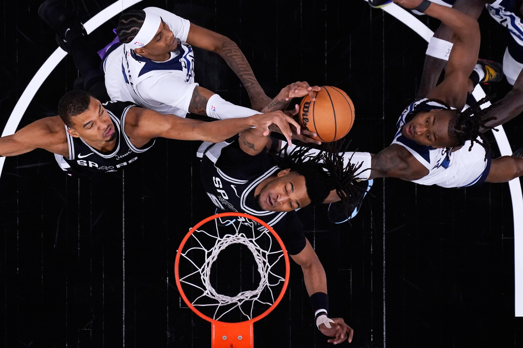 San Antonio Spurs forward Victor Wembanyama (1) and guard Stephon Castle (5) battle Minnesota Timberwolves forward Jaden McDaniels, center, and guard Ayo Dosunmu, right, for a rebound during the first half of Game 5 of an NBA basketball second-round playoffs series in Minneapolis, Tuesday, May 12, 2026. (AP Photo/Eric Gay)