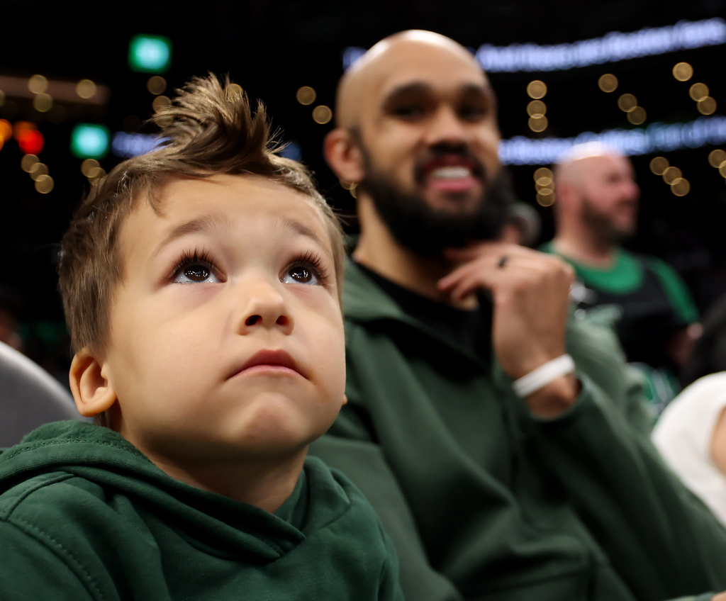 Boston Celtics guard Derrick White, and his son, Daxton, watch the action during the first half of an NBA basketball game against Orlando Magic, Sunday, April 12, 2026, in Boston. White did not play. (AP Photo/Mark Stockwell)