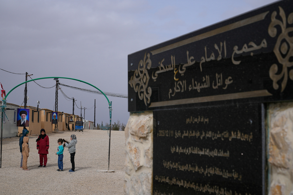 Syrian Shiite girls gather at the Imam Ali Housing Compound, where hundreds of mostly Lebanese and Syrian Shiite Muslims displaced from Syria reside, in Hermel, northeast Lebanon, Friday, Jan. 30, 2026. The Arabic words right, read:"The Imam Ali Housing Compound, families of the honorable martyrs." (AP Photo/Hussein Malla)