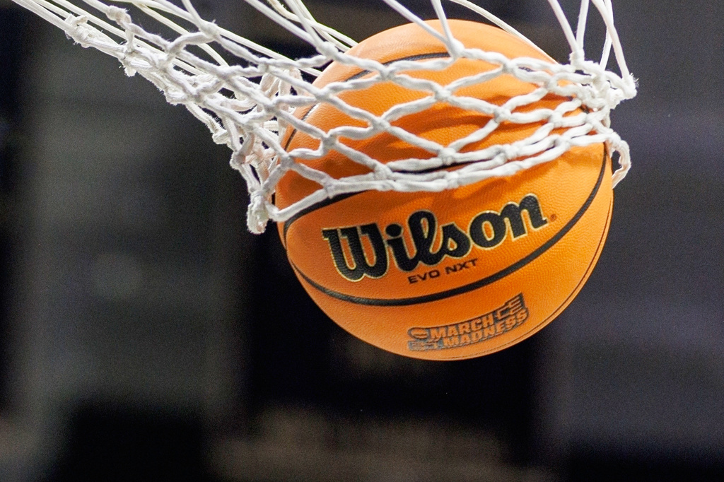 FILE - A basketball with a March Madness logo is seen going through a net prior to a second round of the NCAA college basketball tournament between Notre Dame and Michigan, March 23, 2025, in South Bend, Ind. (AP Photo/John Mersits, File)