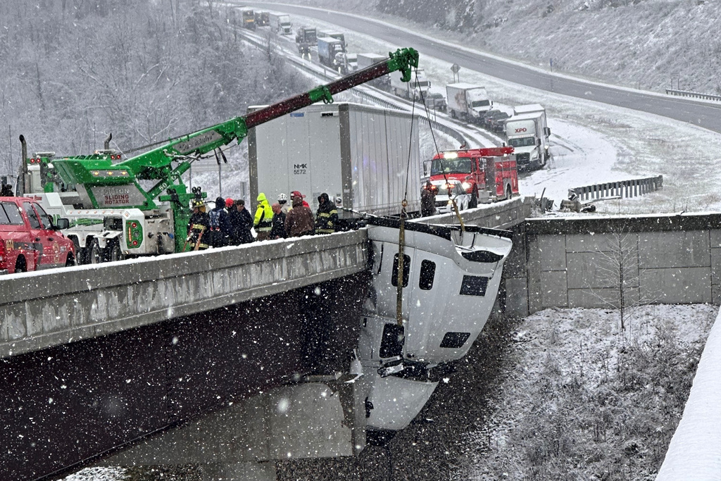 This photo provided by Vickie Flora shows crews working to remove a truck cab dangling from a bridge along U.S. Route 35 after it crashed in icy conditions Tuesday, Dec. 2, 2025, in Southside, W.Va. (Vickie Flora via AP)