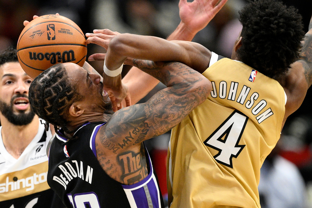 Washington Wizards guard AJ Johnson (4) fouls Sacramento Kings guard DeMar DeRozan, front left, during the first half of an NBA basketball game, Sunday, Feb. 1, 2026, in Washington. (AP Photo/Nick Wass)