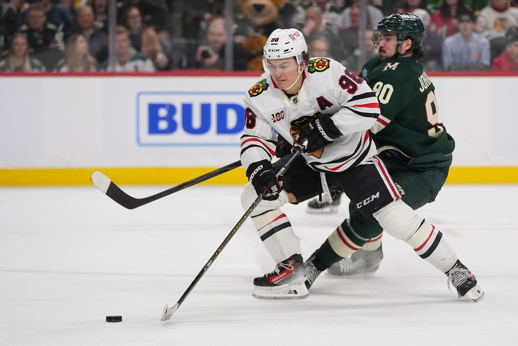 Chicago Blackhawks center Connor Bedard (98) skates with the puck as Minnesota Wild left wing Marcus Johansson (90) defends during the second period of an NHL hockey game, Thursday, March 19, 2026, in St. Paul, Minn. (AP Photo/Abbie Parr)