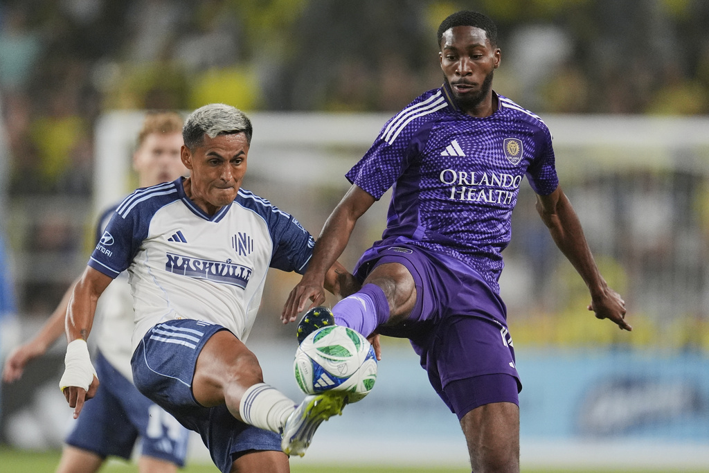Nashville SC midfielder Andy Najar, left, kicks the ball past Orlando City forward Tyrese Spicer, right, during the first half of an MLS soccer match Saturday, Aug. 23, 2025, in Nashville, Tenn. (AP Photo/George Walker IV)