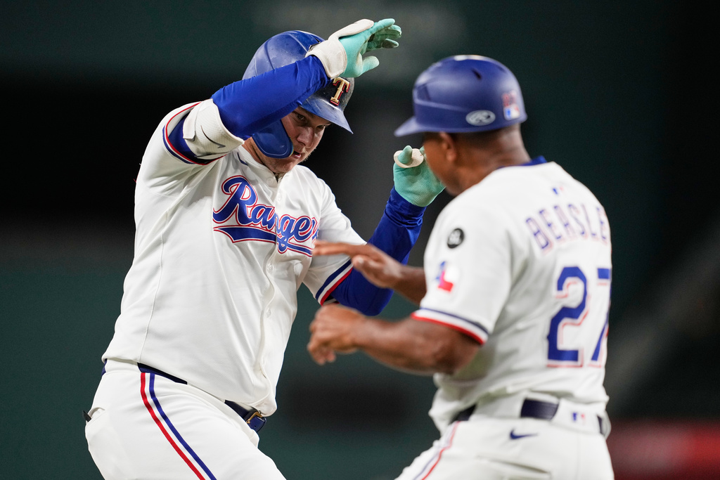 Texas Rangers' Joc Pederson, left, and third base coach Tony Beasley (27) celebrate Pederson's solo home run in the first inning of a baseball game against the Minnesota Twins Tuesday, Sept. 23, 2025, in Arlington, Texas. (AP Photo/Tony Gutierrez)