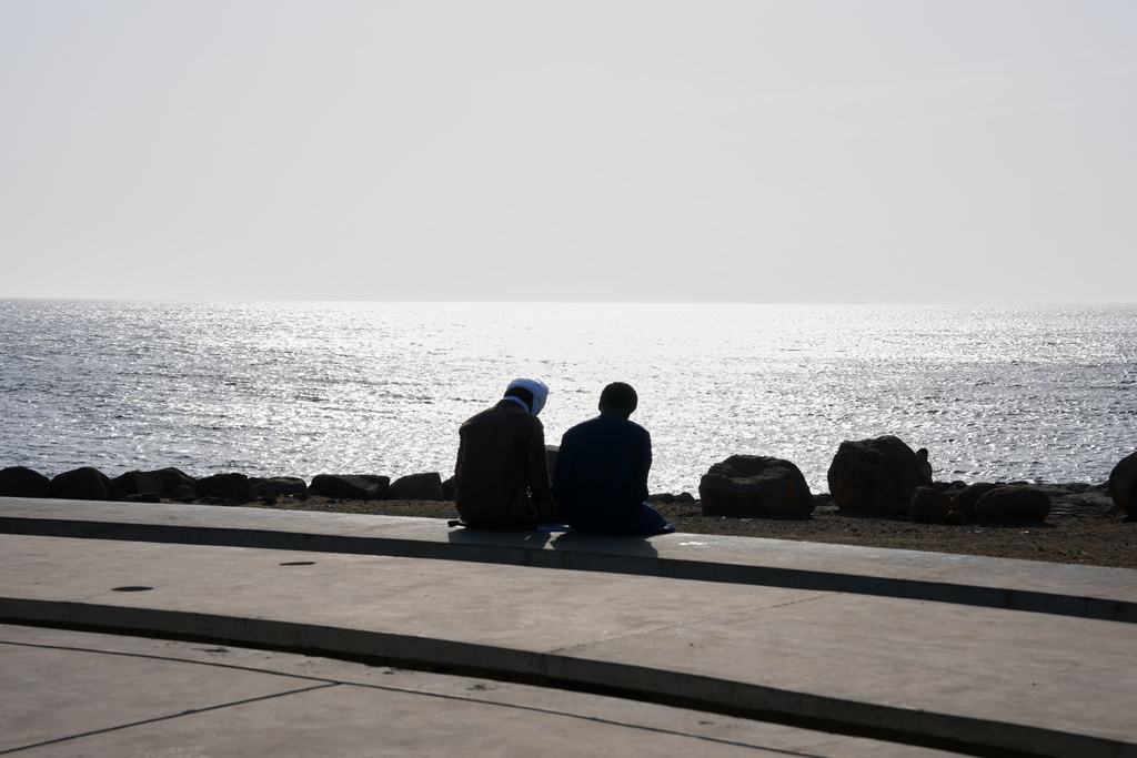 Young men sit at a beach in Dakar, Senegal, Wednesday, March 18, 2026. (AP Photo/Misper Apawu)