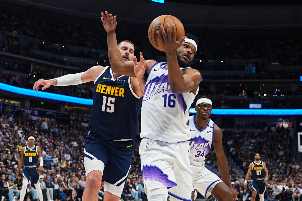 Utah Jazz guard Elijah Harkless, front, pulls in a loose ball as Denver Nuggets center Nikola Jokić defends in the first half of an NBA basketball game Friday, March 27, 2026, in Denver. (AP Photo/David Zalubowski)