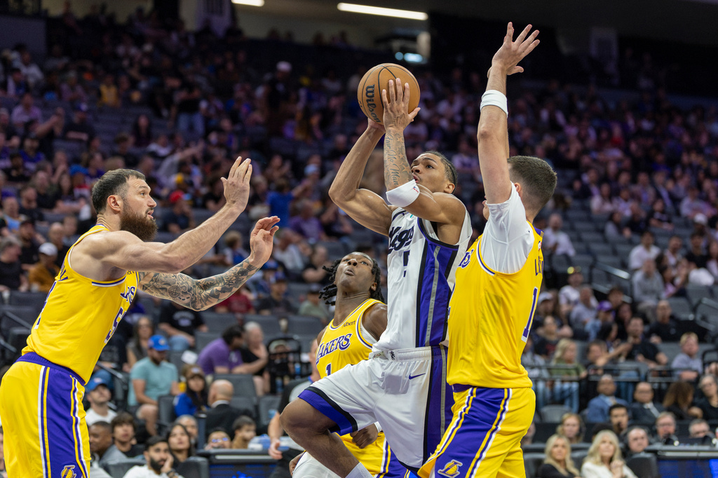 Sacramento Kings guard Darius Acuff Jr. (5) goes up for a layup with Los Angeles Lakers forwards Sandro Mamukelashvili, left, and Jake LaRavia, right, defending during the second half of a preseason NBA basketball game Monday, Oct. 5, 2026, in Sacramento, Calif. (AP Photo/Sara Nevis)