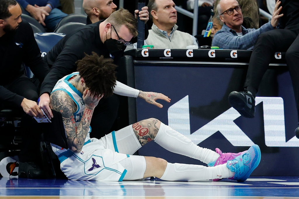 Charlotte Hornets guard LaMelo Ball holds his head after colliding with head coach Charles Lee during the first half of an NBA basketball game against the New Orleans Pelicans, in Charlotte, N.C., Monday, Feb. 2, 2026. (AP Photo/Nell Redmond)