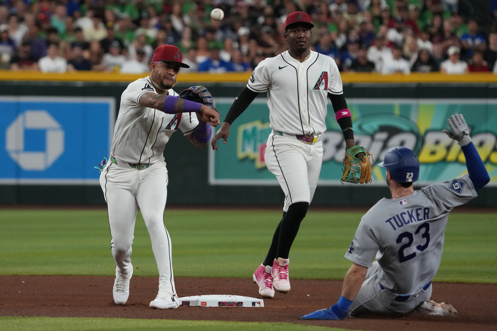 Arizona Diamondbacks second baseman Ketel Marte, left, turns a double play while avoiding Los Angeles Dodgers' Kyle Tucker (23) on a ball hit by Dodgers' Will Smith in the fifth inning of a baseball game, Thursday, June 4, 2026, in Phoenix. (AP Photo/Rick Scuteri)
