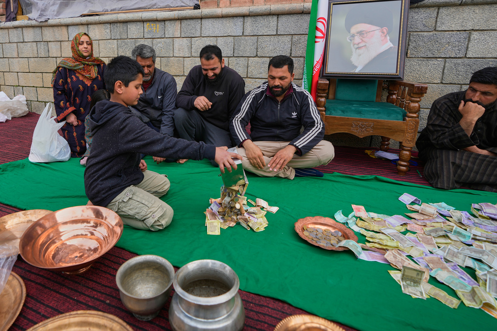 A boy empties his piggy bank to donate his savings during a relief drive for Iran in Budgam, Indian-controlled Kashmir, Monday, March 23, 2026. (AP Photo/Mukhtar Khan)