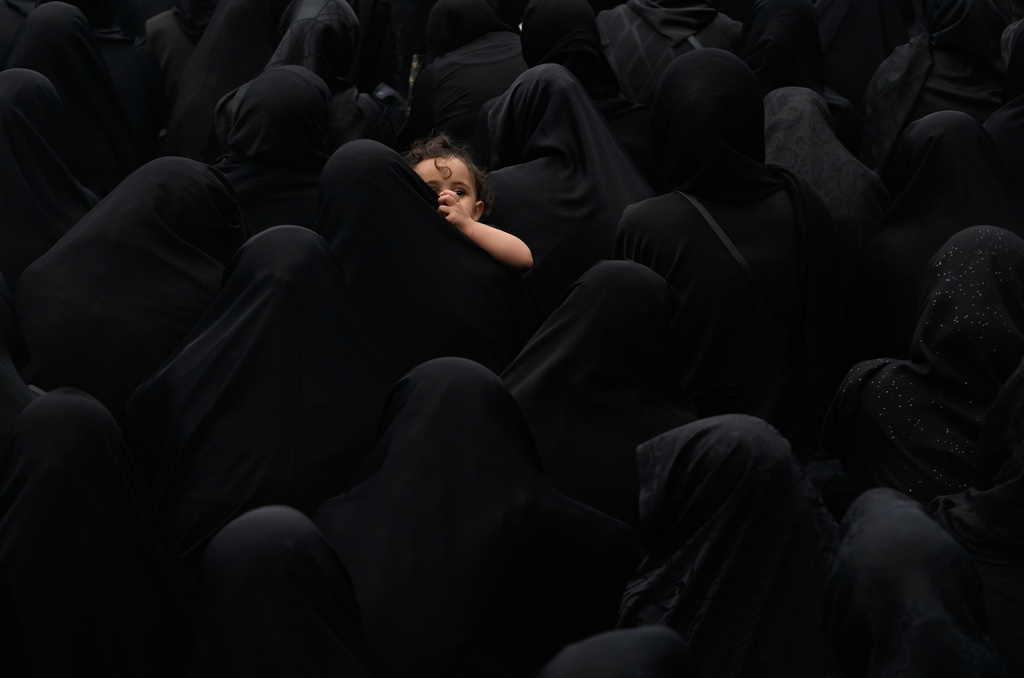 A woman holds a child during a mourning ceremony in Tehran, Iran, Thursday, June 25, 2026, in the holy day of Ashoura which commemorates the martyrdom of Imam Hussein, a grandson of the Prophet Muhammad, and his family and companions at the Battle of Karbala in A.D. 680, in present-day Iraq, after refusing to pledge allegiance to the Umayyad caliphate. (AP Photo/Vahid Salemi)