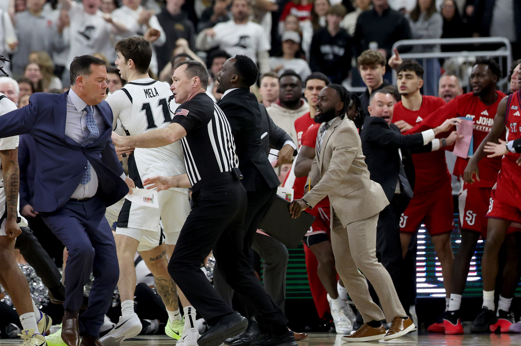 A game official separates St. John's coaches and players after a fight broke out during the second half of an NCAA college basketball game against Providence, Saturday, Feb. 14, 2026, in Providence, R.I. (AP Photo/Mark Stockwell)