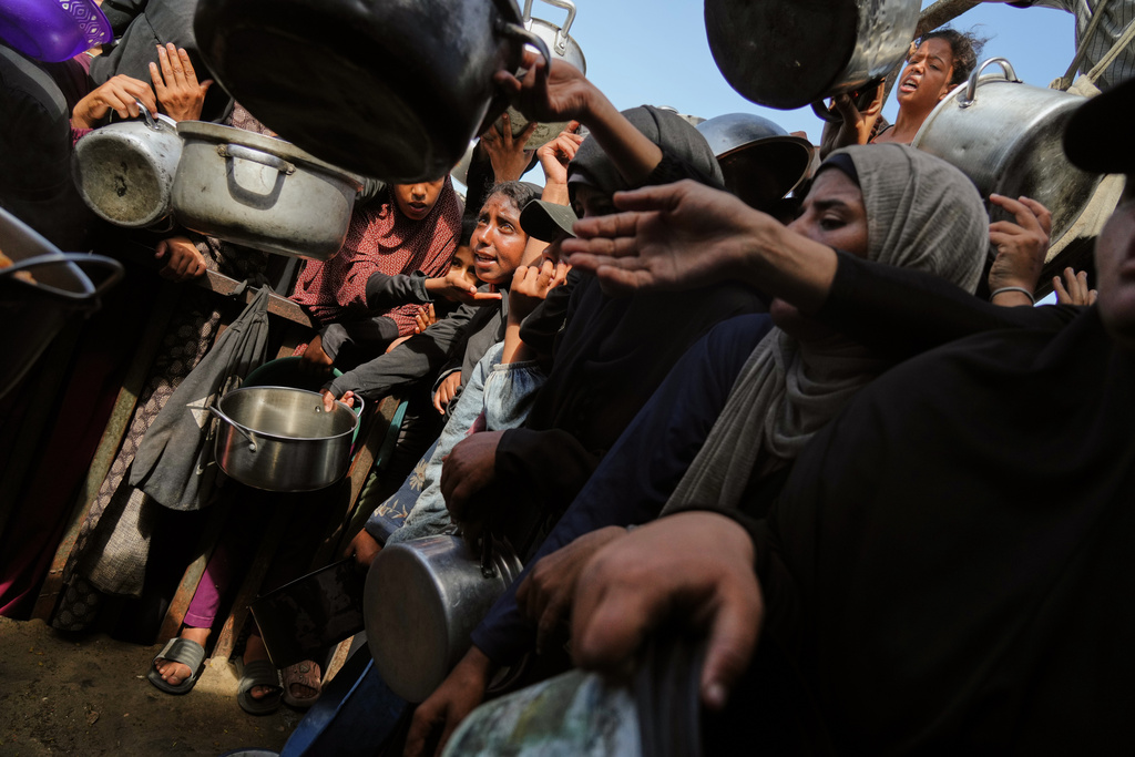 Palestinians struggle to get donated food at a community kitchen in Khan Younis, southern Gaza Strip, Sunday, Oct. 5, 2025. (AP Photo/Jehad Alshrafi)