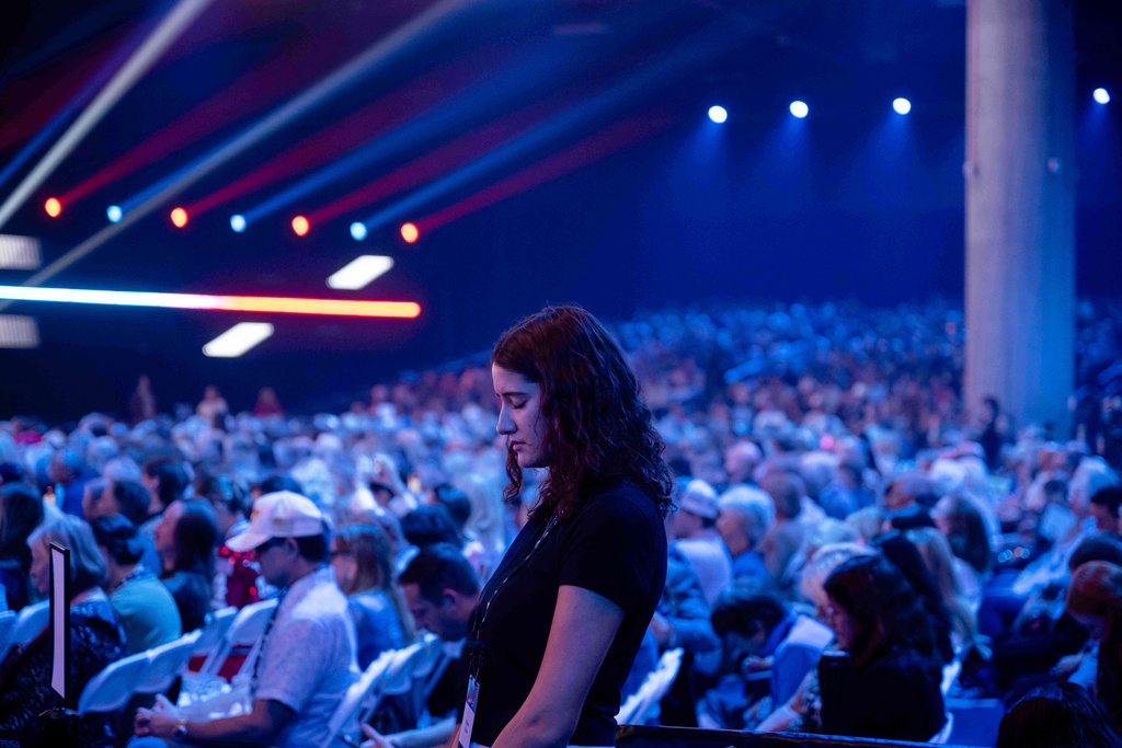 An attendee prays during Turning Point USA's AmericaFest 2025, Thursday, Dec. 18, 2025, in Phoenix. (AP Photo/Jon Cherry)