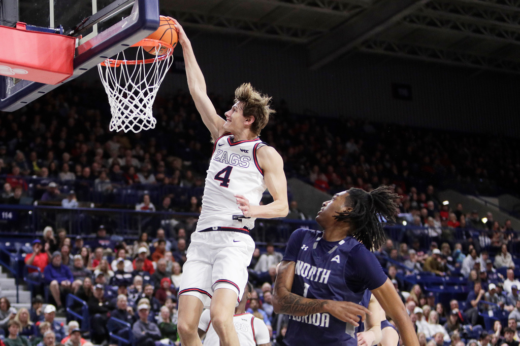 Gonzaga guard Davis Fogle (4) dunks next to North Florida forward BJ Plummer (1) during the second half of an NCAA college basketball game, Sunday, Dec. 7, 2025, in Spokane, Wash. (AP Photo/Young Kwak)