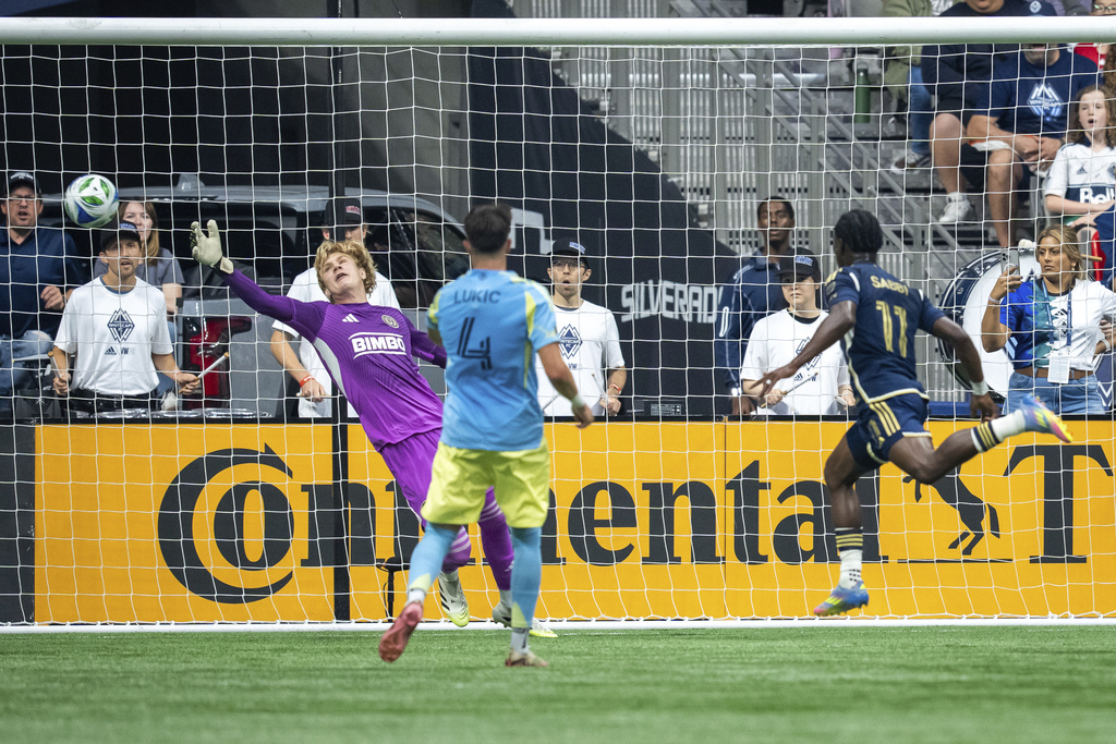 Vancouver Whitecaps' Emmanuel Sabbi (11) scores on Philadelphia Union goalkeeper Andrew Rick, left, as Jovan Lukic (4) watches during the first half of an MLS soccer match in Vancouver, British Columbia, Saturday, Sept. 13, 2025. (Ethan Cairns/The Canadian Press via AP)