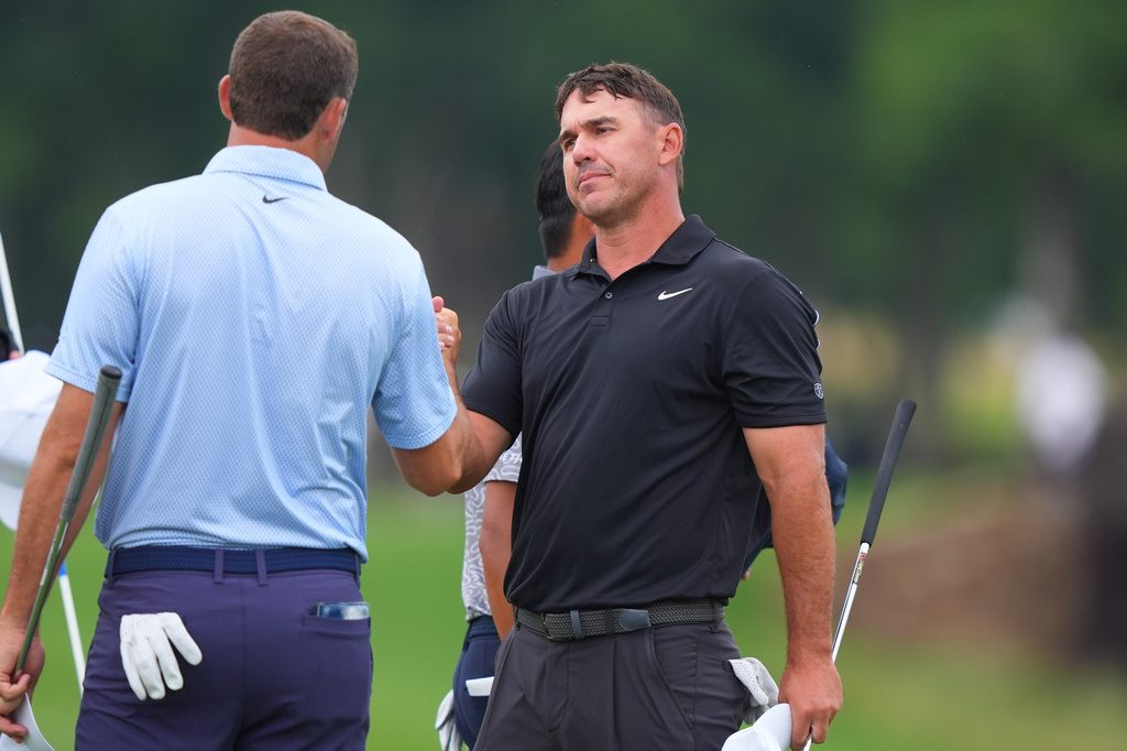 Brooks Koepka, right, shakes hands with Scottie Scheffler after playing their final hole in the first round of the Byron Nelson golf tournament in McKinney, Texas, Thursday, May 21, 2026. (AP Photo/LM Otero)