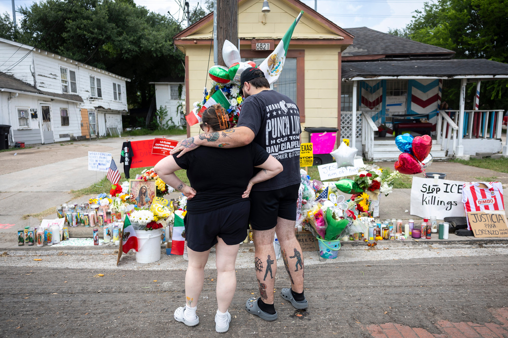 A couple spends a moment after placing flowers at the site where Lorenzo Salgado Araujo was shot by an ICE officer in Houston, Friday, July 10, 2026. (AP Photo/Annie Mulligan)