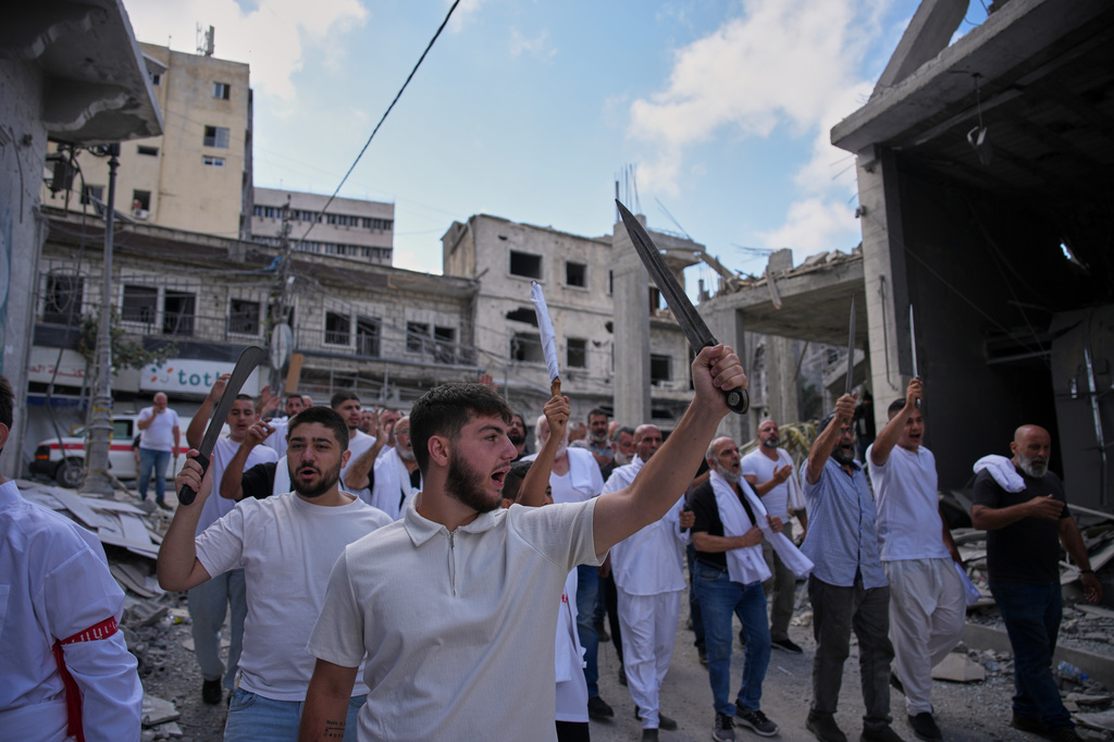 Lebanese Shiite men raise swords during an Ashoura procession, when Shiites commemorate the martyrdom of Imam Hussein, the grandson of the Prophet Muhammad, in Nabatiyeh, southern Lebanon, Friday, June 26, 2026. (AP Photo/Hassan Ammar)