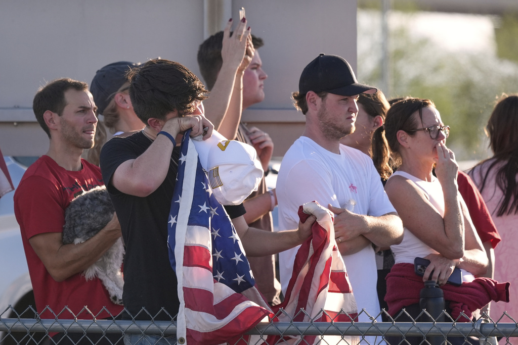 People watch a hearse containing the body of Charlie Kirk, the CEO and co-founder of Turning Point USA, who was shot and killed on Wednesday leave after the body arrived aboard Air Force Two at Phoenix Sky Harbor International Airport, Thursday, Sept. 11, 2025, in Phoenix. (AP Photo/Ross D. Franklin)