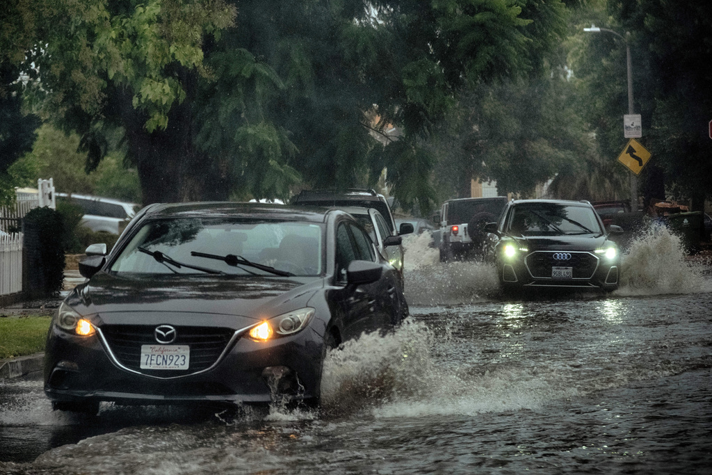Morning commuters maneuver a flooded street during a flash flood warning in the San Fernando Valley section of Los Angeles on Tuesday, Oct. 14, 2025. (AP Photo/Richard Vogel)