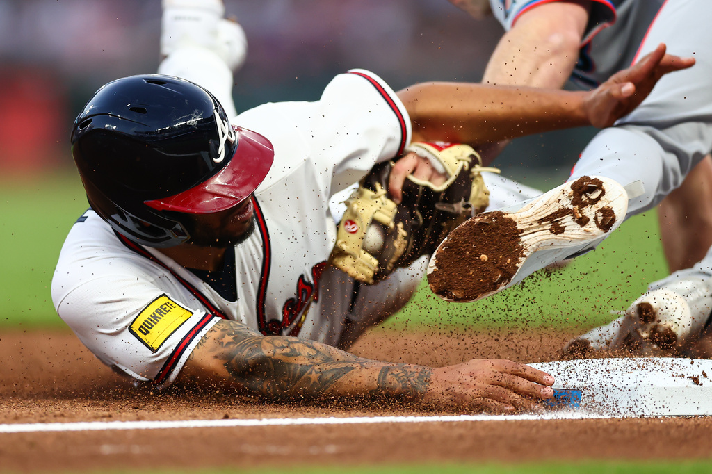 Atlanta Braves designated hitter Dominic Smith, left, is tagged out by Miami Marlins third baseman Graham Pauley, right, in the third inning of a baseball game, Monday, April 13, 2026, in Atlanta. (AP Photo/Colin Hubbard)