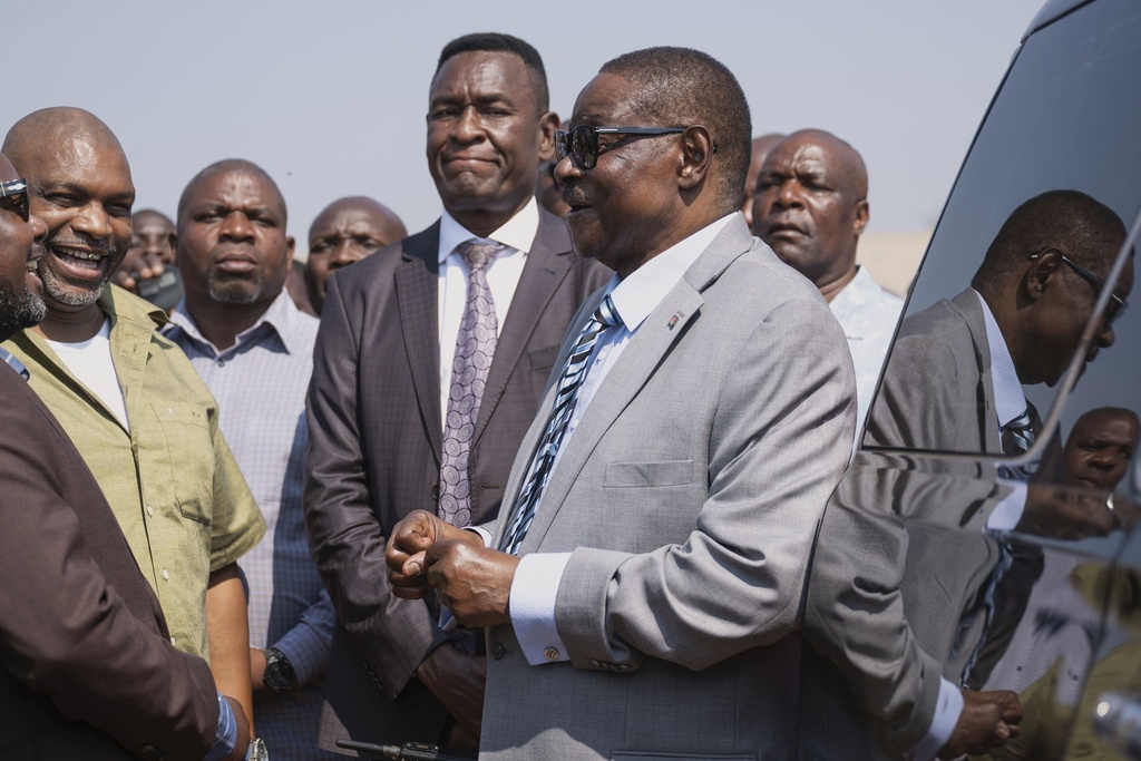 Malawi's presidential candidate, former President Peter Mutharika, right, shares a light moment with officials following casting his vote in Thyolo District, Malawi, Tuesday, Sept. 16, 2025. (AP Photo/Thoko Chikondi)