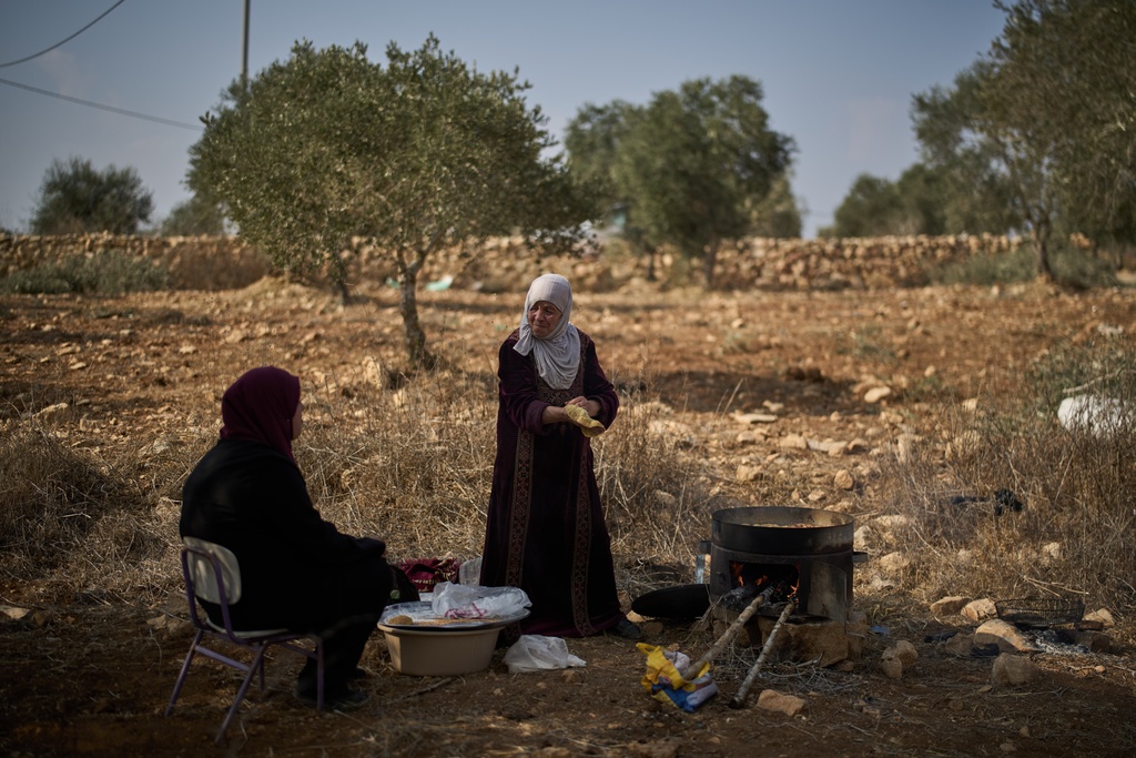 Halwa Shbana, 72, bakes traditional sweet bread as Palestinians harvest olives with the assistance of foreign volunteers in the West Bank village of Sinjil, Thursday, Nov. 13, 2025. (AP Photo/Leo Correa)